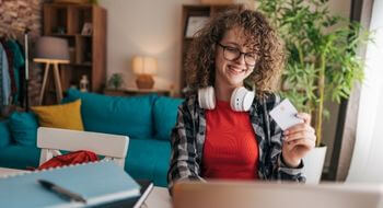 Teen is checking bank account on computer and looking at debit card.